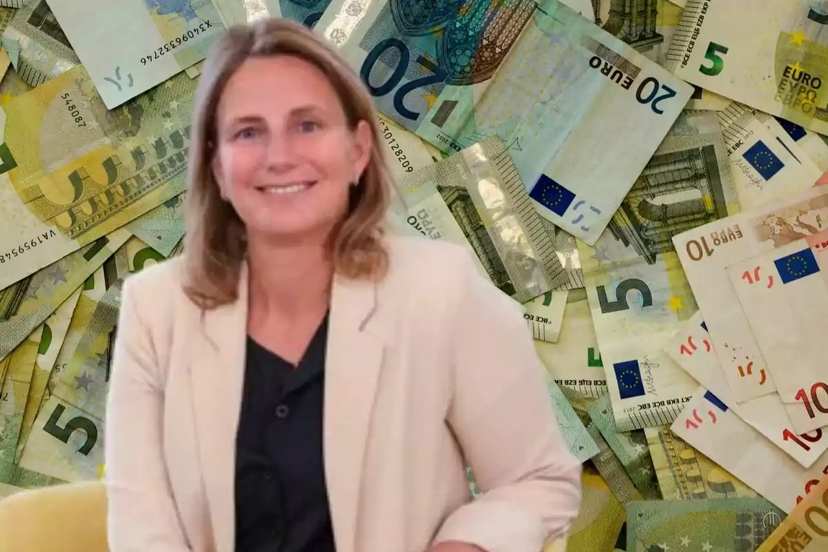 Dona somrient amb jaqueta clara i brusa fosca asseguda davant d’un fons de bitllets d’euro de diferents denominacions