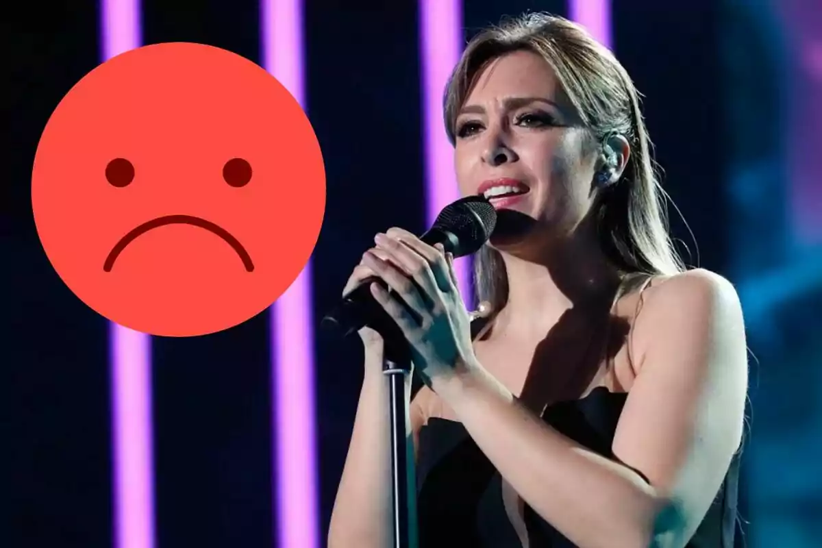 Mujer cantando en un escenario con luces moradas de fondo y un emoji de cara triste grande a la izquierda