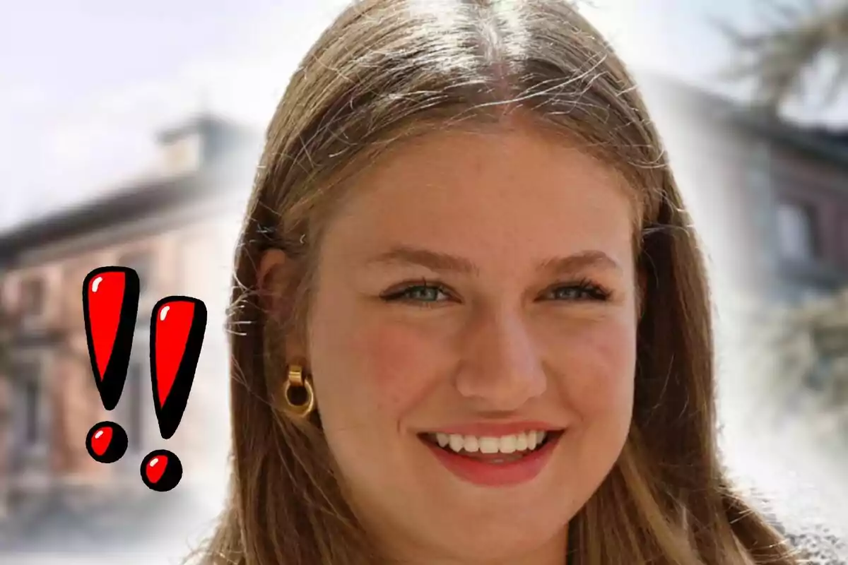 Primer plano de Leonor de Borbón sonriente con cabello rubio y pendientes dorados al frente de un fondo desenfocado y dos signos de exclamación rojos dibujados a la izquierda.