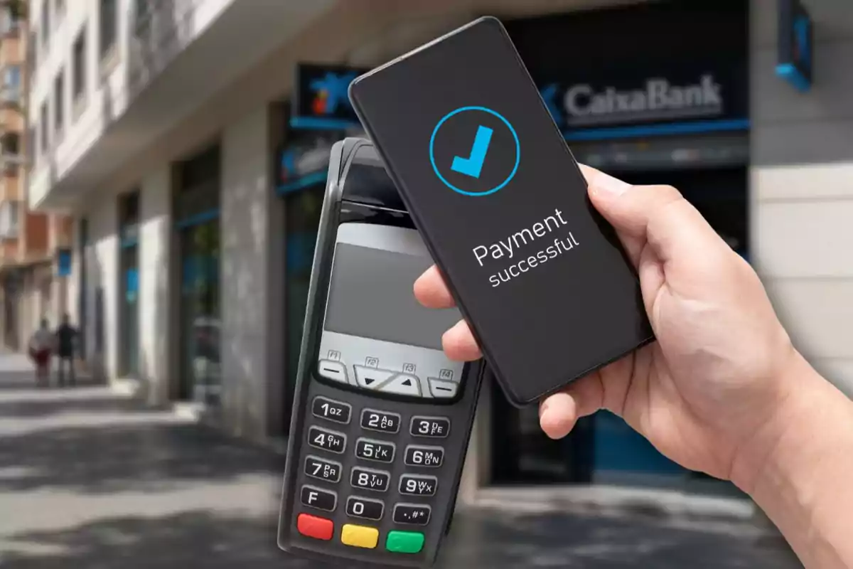 Persona realitzant un pagament amb èxit amb el seu telèfon mòbil mitjançant tecnologia contactless en un datàfon davant d’una sucursal bancària Persona realitzant un pagament amb èxit amb el seu telèfon mòbil mitjançant tecnologia contactless en un datàfon davant d’una sucursal bancària