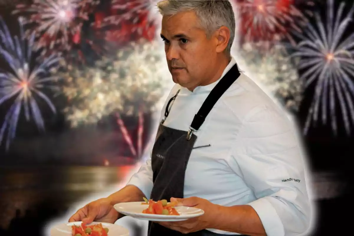 Chef con cabello canoso y uniforme blanco sostiene dos platos de comida mientras al fondo se observan fuegos artificiales en el cielo nocturno.