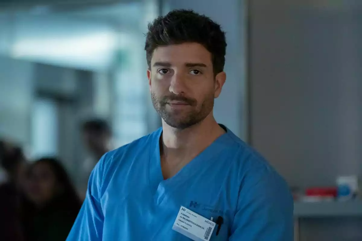 Pablo Alborán jove amb barba i cabell curt portant uniforme mèdic blau i una targeta d’identificació en un entorn hospitalari a Respira. Pablo Alborán jove amb barba i cabell curt portant uniforme mèdic blau i una targeta d’identificació en un entorn hospitalari a Respira.