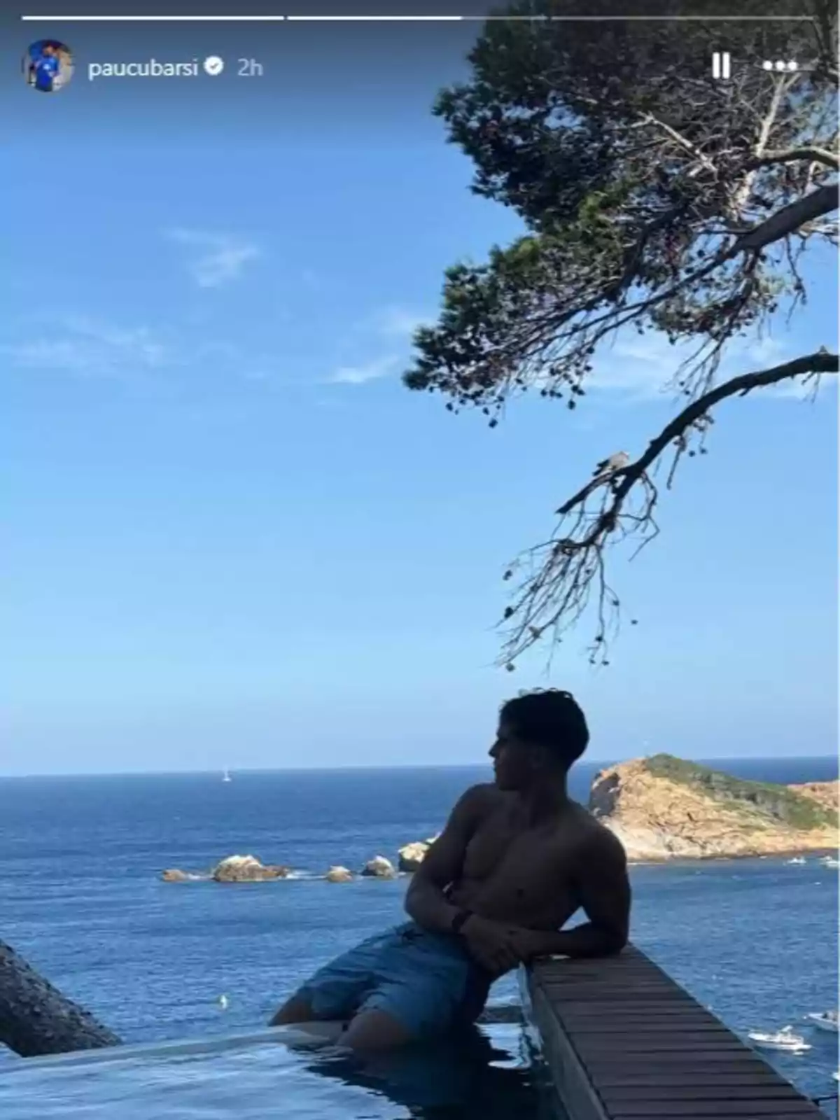 Jove estirat a la vora d’una piscina amb vistes al mar i un paisatge de roques i arbres Jove estirat a la vora d’una piscina amb vistes al mar i un paisatge de roques i arbres