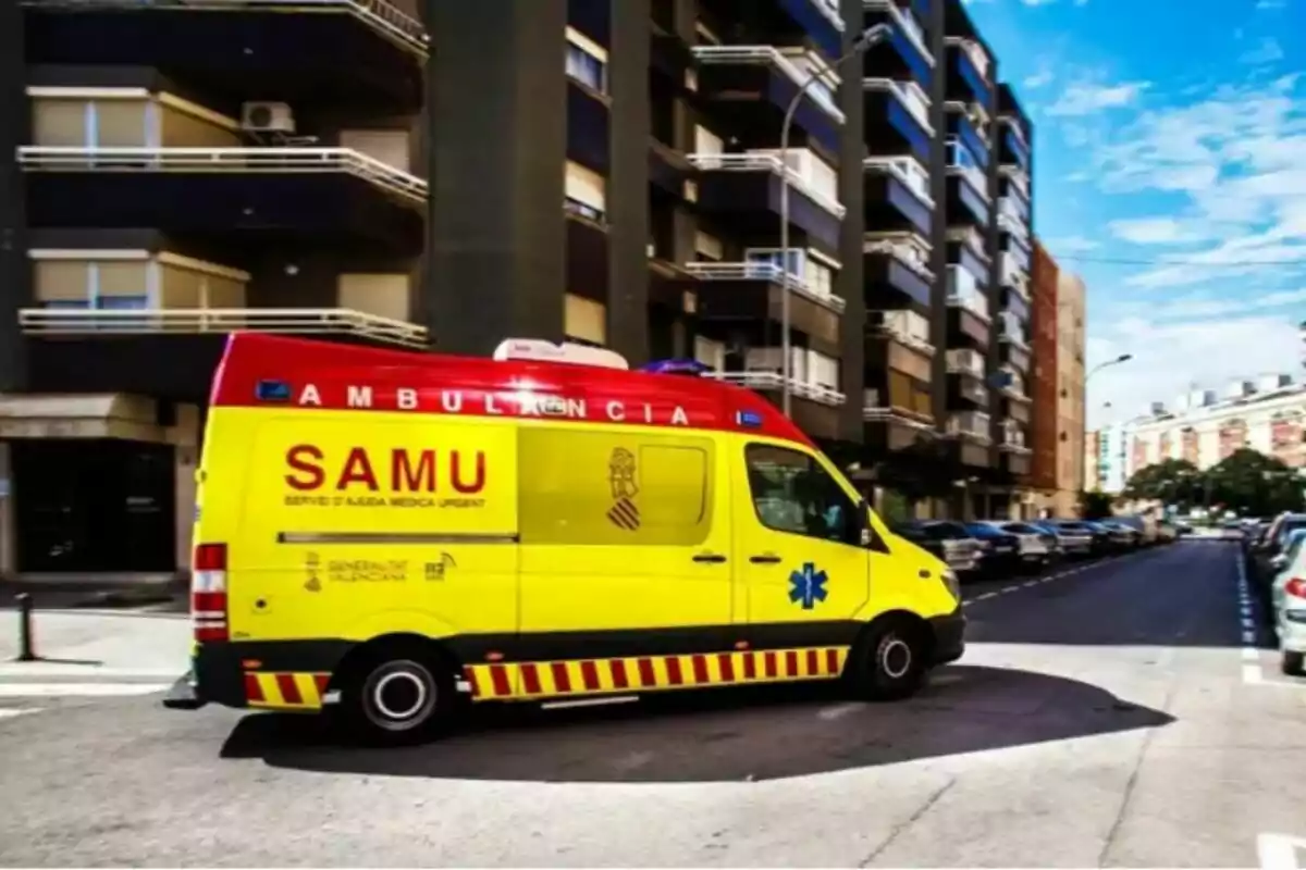 Ambulancia amarilla y roja del SAMU circulando por una calle urbana rodeada de edificios y coches estacionados Ambulancia amarilla y roja del SAMU circulando por una calle urbana rodeada de edificios y coches estacionados