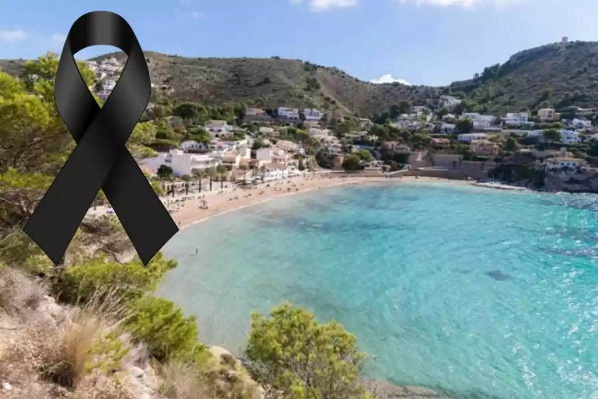 Playa con casas en la ladera y un lazo negro de luto en la esquina superior izquierda