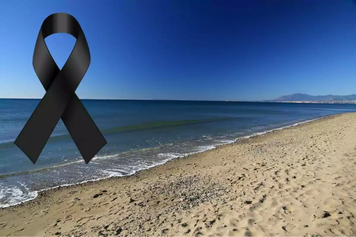 Platja amb cel serè i un llaç negre de dol a la cantonada superior esquerra
