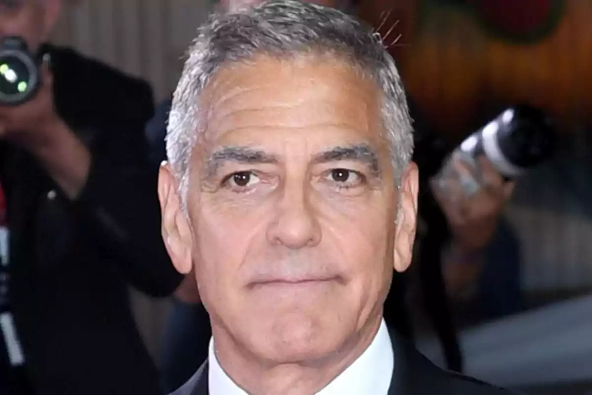 George Clooney amb vestit fosc en un esdeveniment amb fotògrafs al fons George Clooney amb vestit fosc en un esdeveniment amb fotògrafs al fons