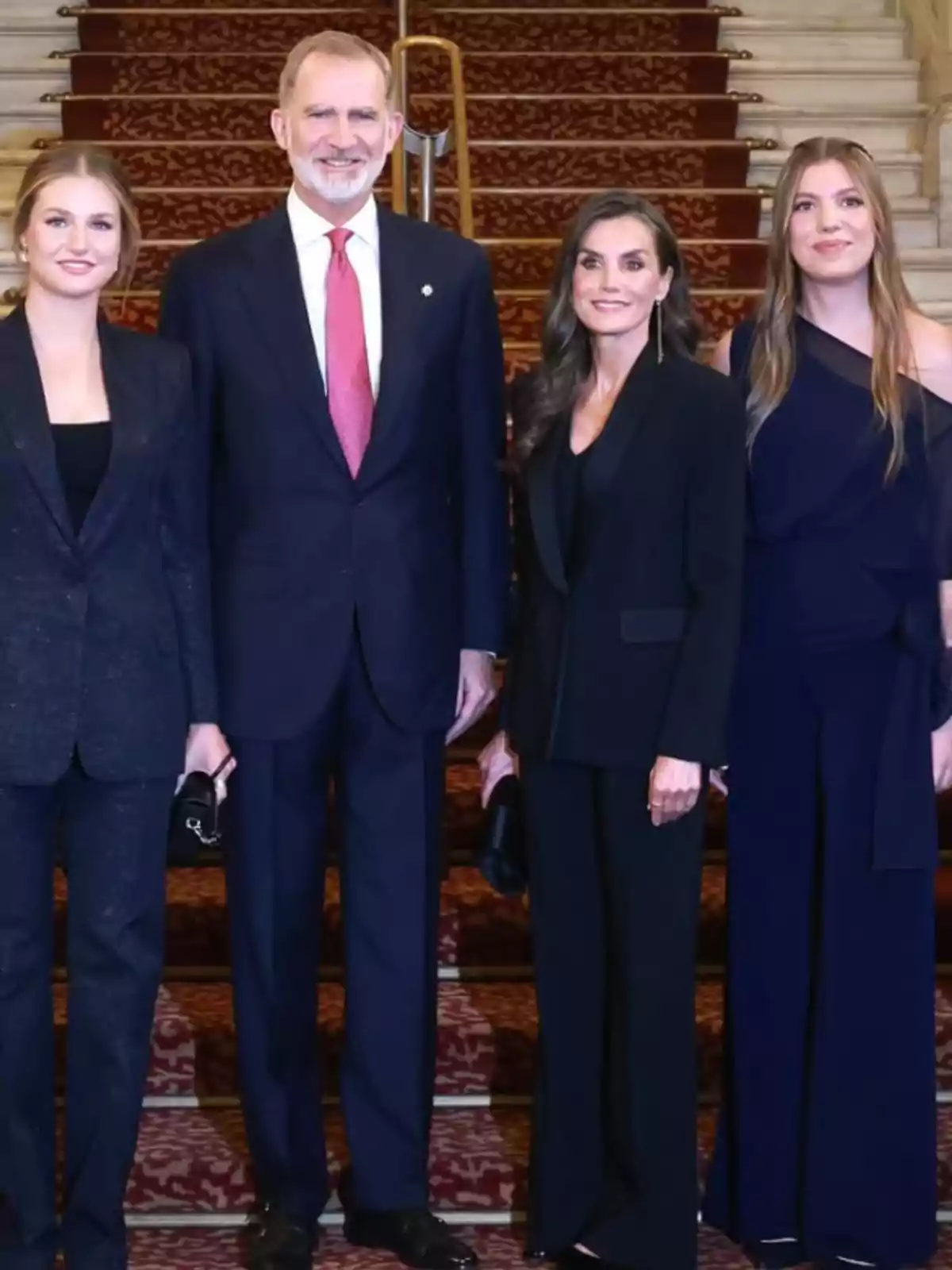Quatre persones elegantment vestides posen juntes en una escala enmoquetada. Quatre persones elegantment vestides posen juntes en una escala enmoquetada.