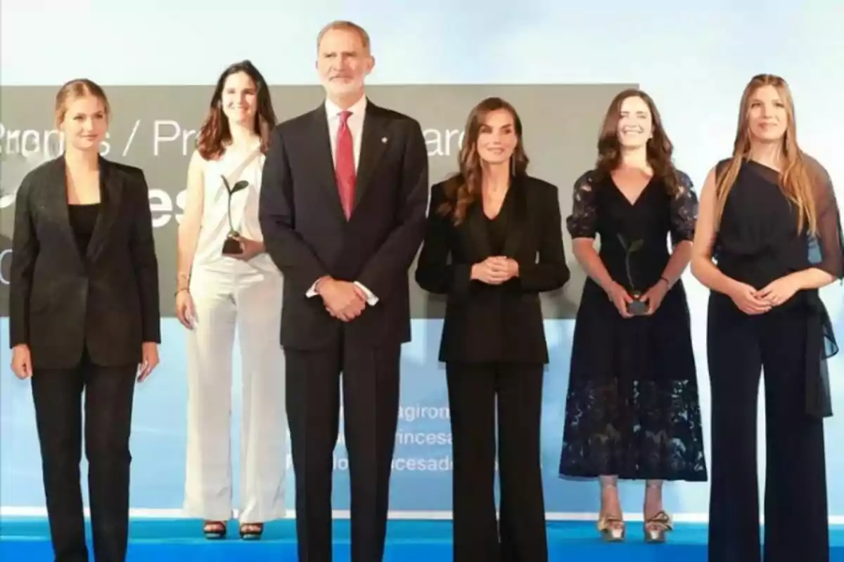 Sis persones posen en un escenari durant una cerimònia de lliurament de premis, dues d'elles sostenen petits trofeus en forma de planta. Sis persones posen en un escenari durant una cerimònia de lliurament de premis, dues d'elles sostenen petits trofeus en forma de planta.