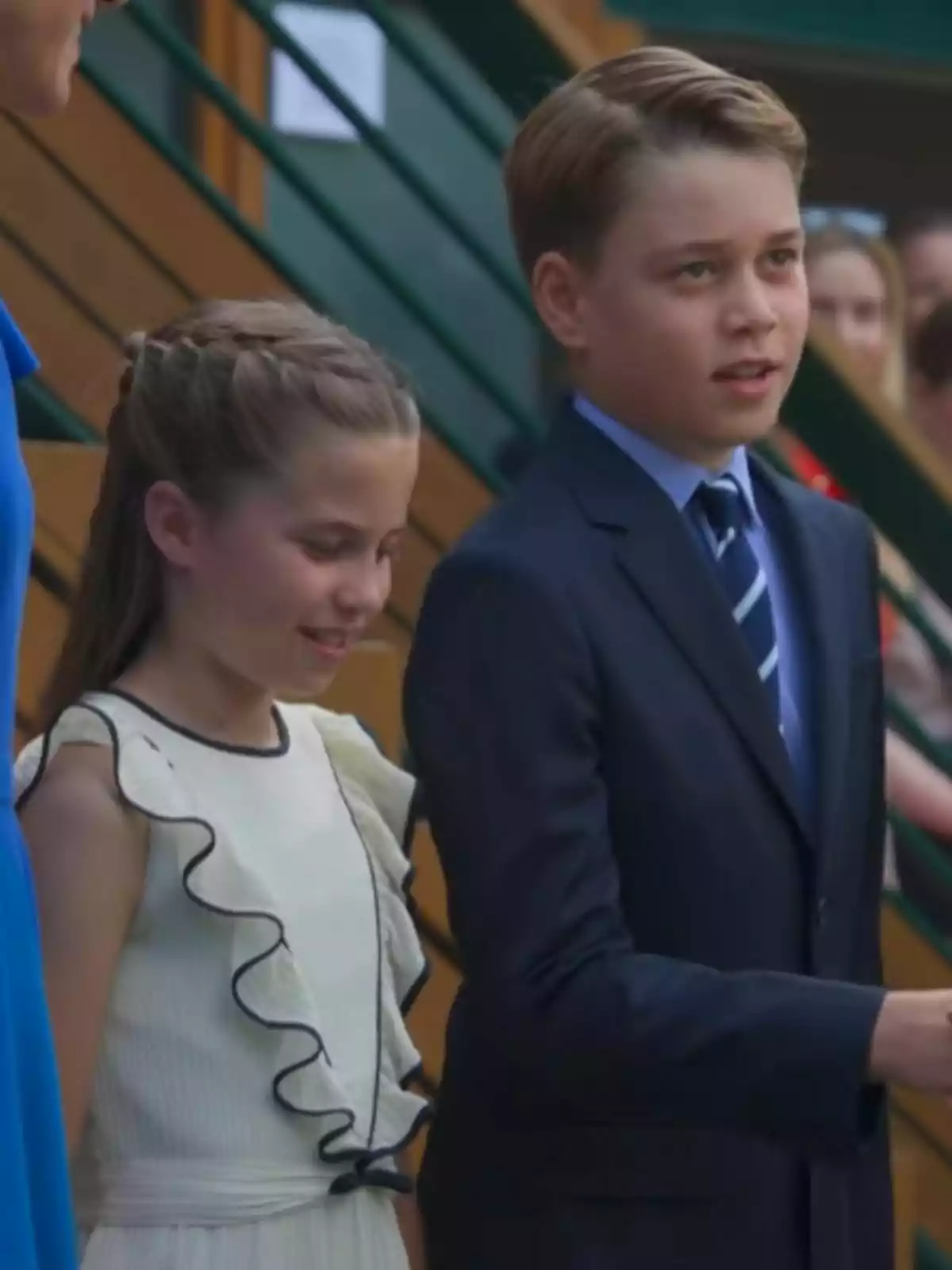 Dos nens ben vestits, una és la princesa Charlotte amb un vestit blanc amb volants i l’altre és el príncep George amb un vestit blau i corbata, estan drets junts en un esdeveniment formal. Dos nens ben vestits, una és la princesa Charlotte amb un vestit blanc amb volants i l’altre és el príncep George amb un vestit blau i corbata, estan drets junts en un esdeveniment formal.