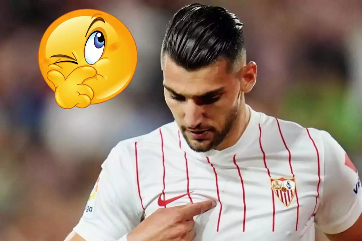 Futbolista con camiseta blanca de rayas rojas señalando el escudo del Sevilla mientras un emoji pensativo aparece a su lado