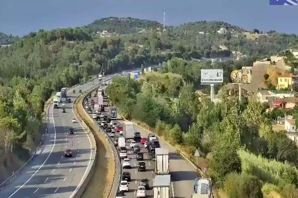 Carretera amb trànsit dens en un sentit i turons verds al voltant