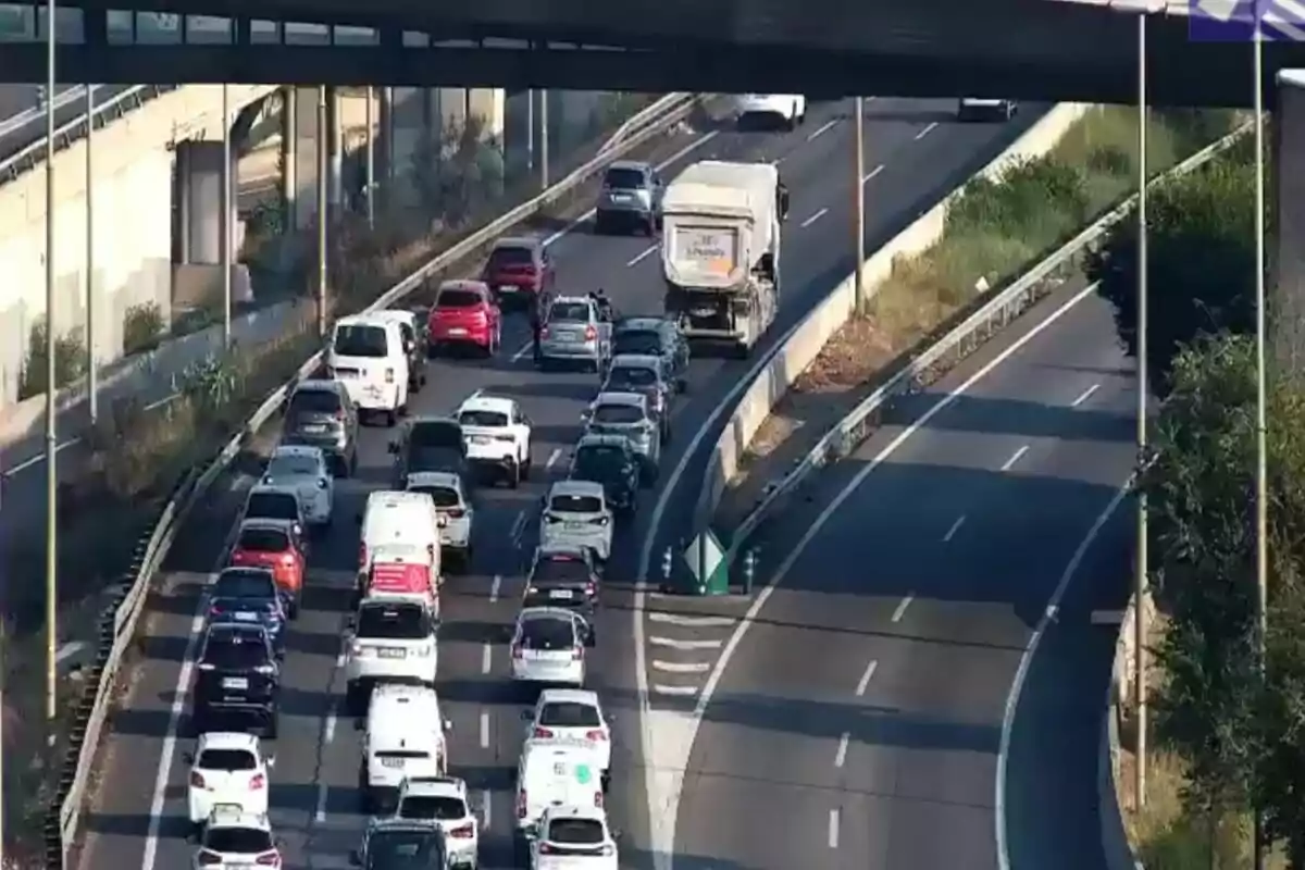 Tráfico denso en una autopista con varios autos y una camioneta detenidos en varios carriles mientras la vía lateral está vacía