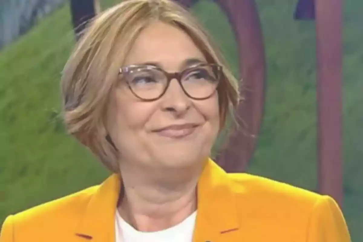 Rosa Lerchundi de cabello corto y rubio con gafas y chaqueta amarilla sonriendo en un entorno de estudio de Informativos Telecinco Rosa Lerchundi de cabello corto y rubio con gafas y chaqueta amarilla sonriendo en un entorno de estudio de Informativos Telecinco