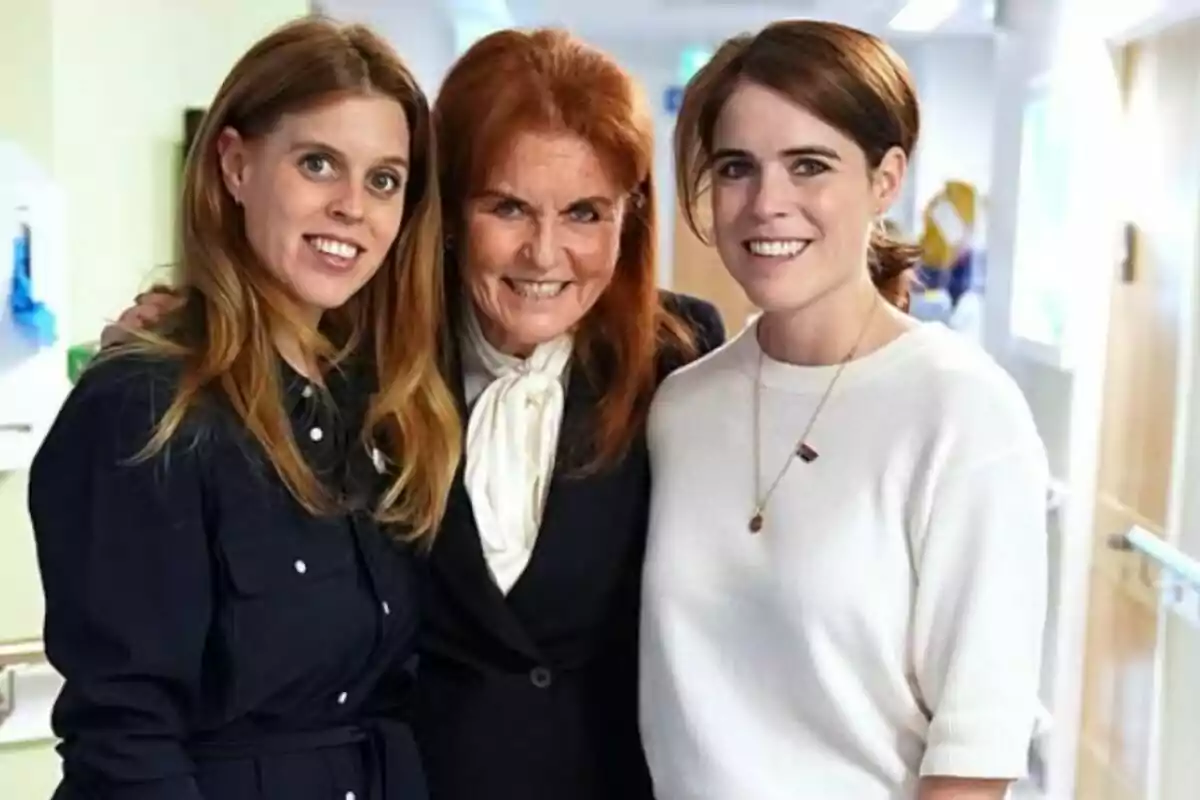 Tres mujeres sonríen y posan juntas en un pasillo iluminado Tres mujeres sonríen y posan juntas en un pasillo iluminado