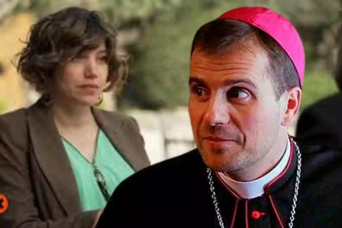 Una dona de cabell curt i arrissat amb jaqueta marró i brusa verda és al fons mentre un home amb vestimenta de bisbe i solidé rosa apareix en primer pla mirant cap a l'esquerra.