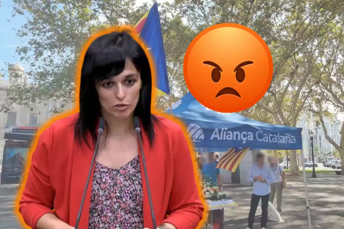 Dona de cabells foscos parlant davant de micròfons amb expressió seriosa, sobre un fons de carpa blava d’Aliança Catalana i un emoji de ràbia gran a la dreta