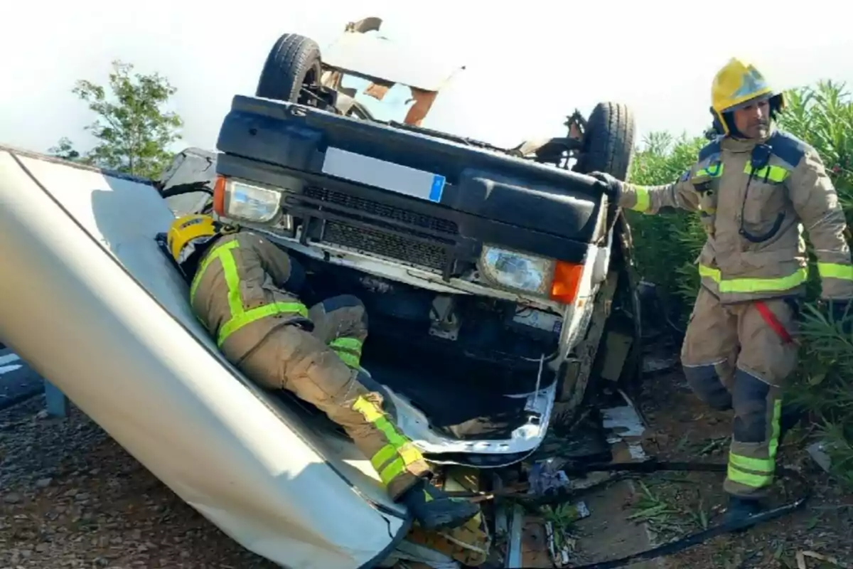 Bomberos trabajando en el rescate tras el vuelco de un vehículo cerca de una carretera Bomberos trabajando en el rescate tras el vuelco de un vehículo cerca de una carretera