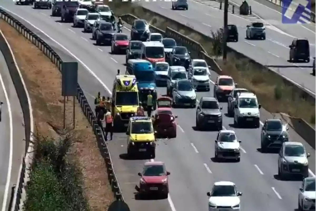Trànsit aturat en una autopista a causa d’un accident amb presència d’ambulàncies i personal d’emergència assistint els implicats.