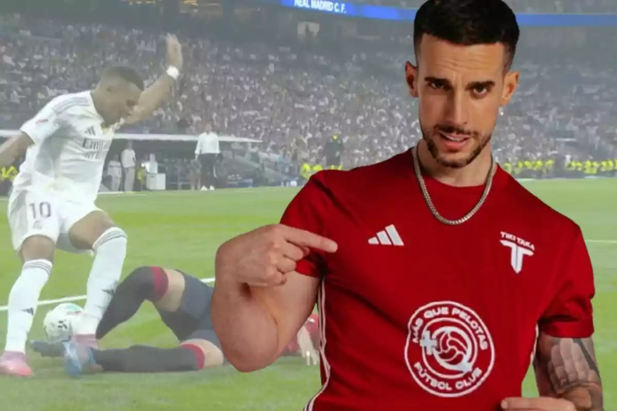 Un hombre con camiseta roja señala el logo de su camiseta mientras al fondo se ve una jugada de fútbol con un jugador de blanco y otro en el suelo en un estadio lleno de público