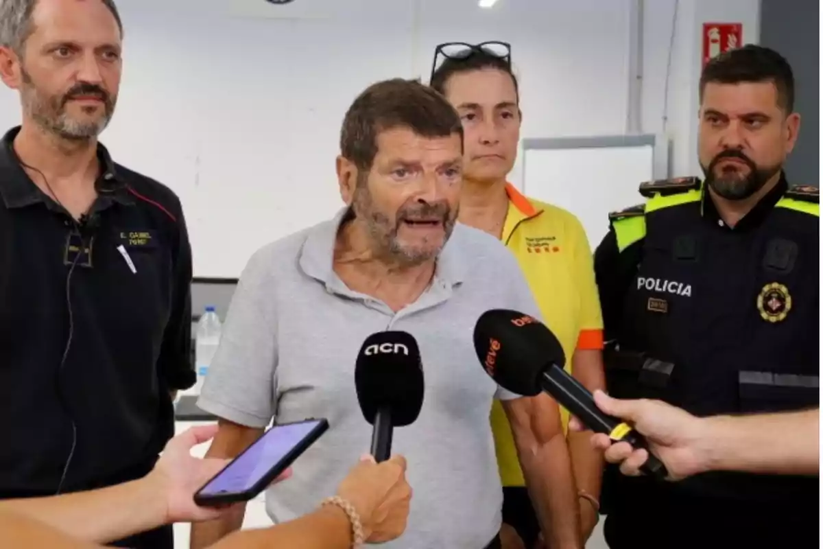 Un home gran parla davant de diversos micròfons envoltat de tres persones, una d’elles amb uniforme de policia i una altra amb uniforme de protecció civil. Un home gran parla davant de diversos micròfons envoltat de tres persones, una d’elles amb uniforme de policia i una altra amb uniforme de protecció civil.