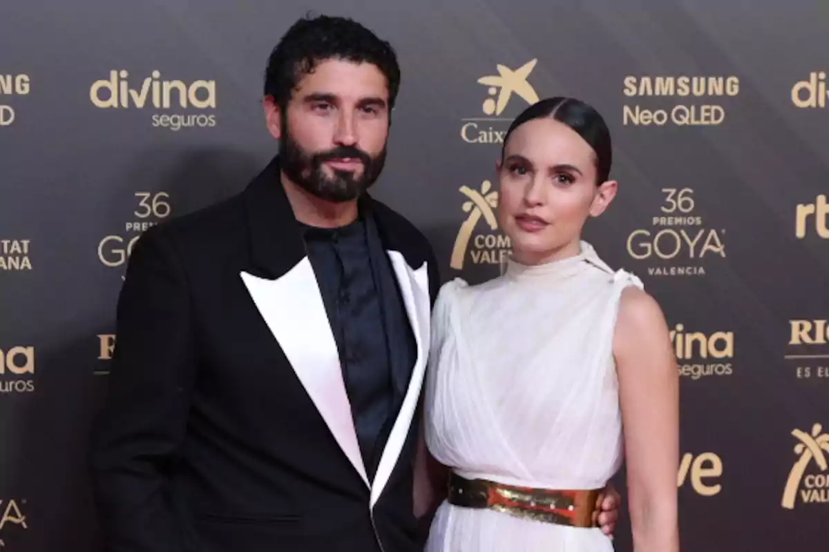 Álex García y Verónica Echegui posando en la alfombra roja de un evento de premiación con fondo de logotipos de patrocinadores y organizadores Álex García y Verónica Echegui posando en la alfombra roja de un evento de premiación con fondo de logotipos de patrocinadores y organizadores