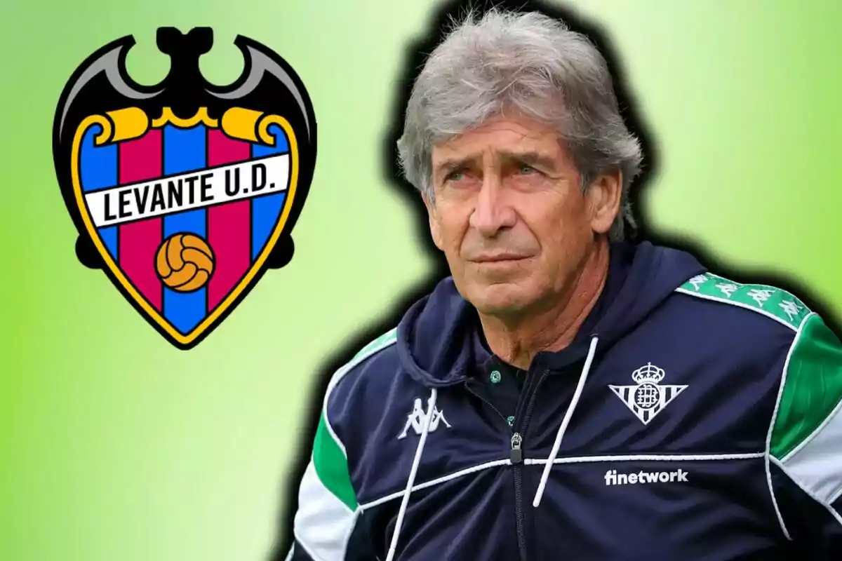 Entrenador de futbol amb jaqueta del Betis al costat de l’escut del Llevant sobre fons verd