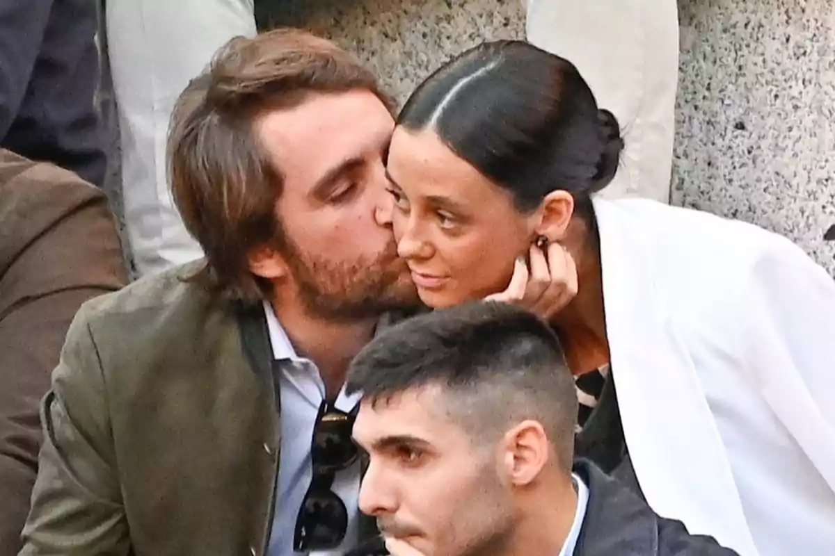 Borja Moreno kisses Victoria Federica on the cheek while she looks at him and smiles slightly in an outdoor setting surrounded by other people. Borja Moreno kisses Victoria Federica on the cheek while she looks at him and smiles slightly in an outdoor setting surrounded by other people.