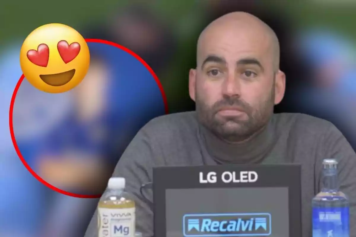 Hombre calvo con barba sentado frente a un micrófono y botellas de agua, con un emoji de cara sonriente con ojos de corazón en la esquina izquierda