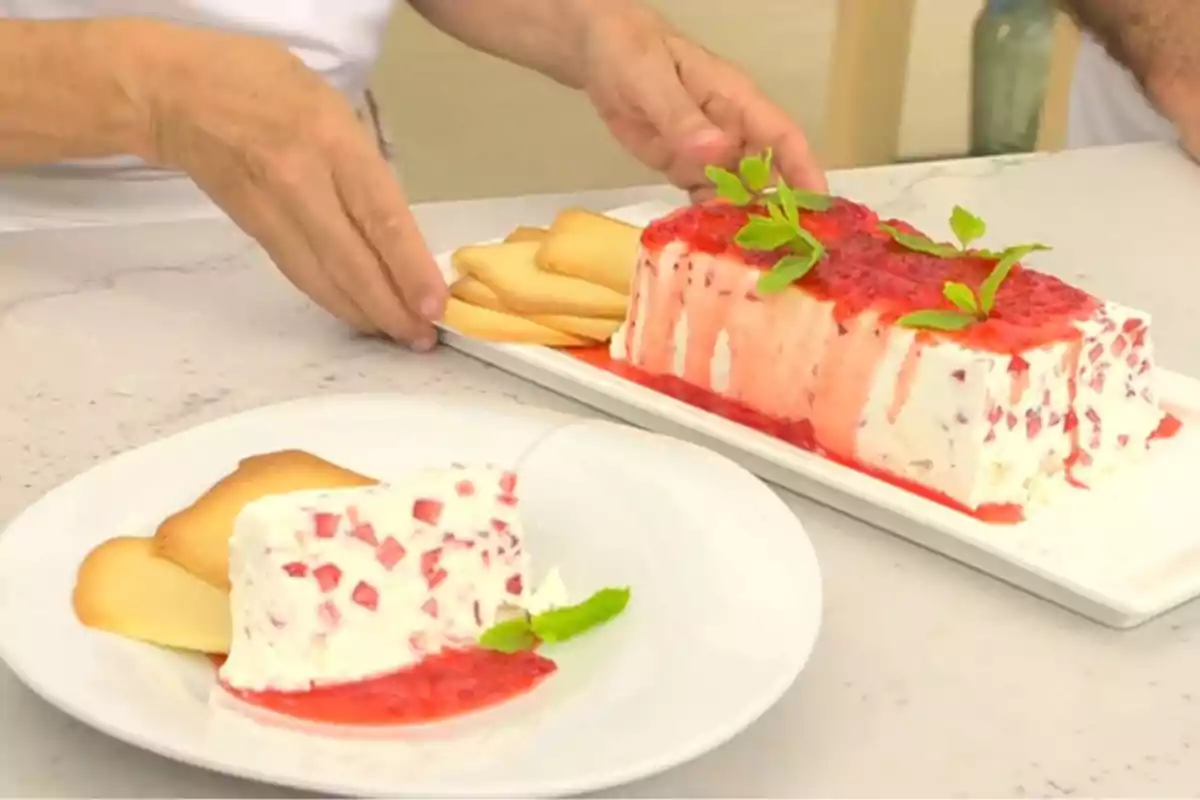 Postres fred de maduixes i crema decorat amb salsa de maduixa i fulles de menta acompanyat de galetes en un plat blanc. Captura de 'Cuina Oberta' Postres fred de maduixes i crema decorat amb salsa de maduixa i fulles de menta acompanyat de galetes en un plat blanc. Captura de 'Cuina Oberta'