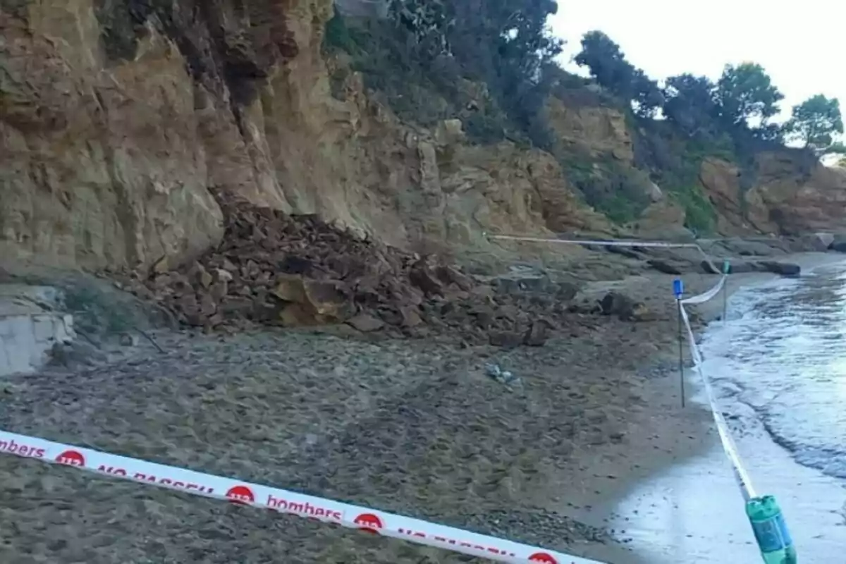 Despreniment de roques en un penya-segat al costat de la platja amb una zona acordonada per precaució.