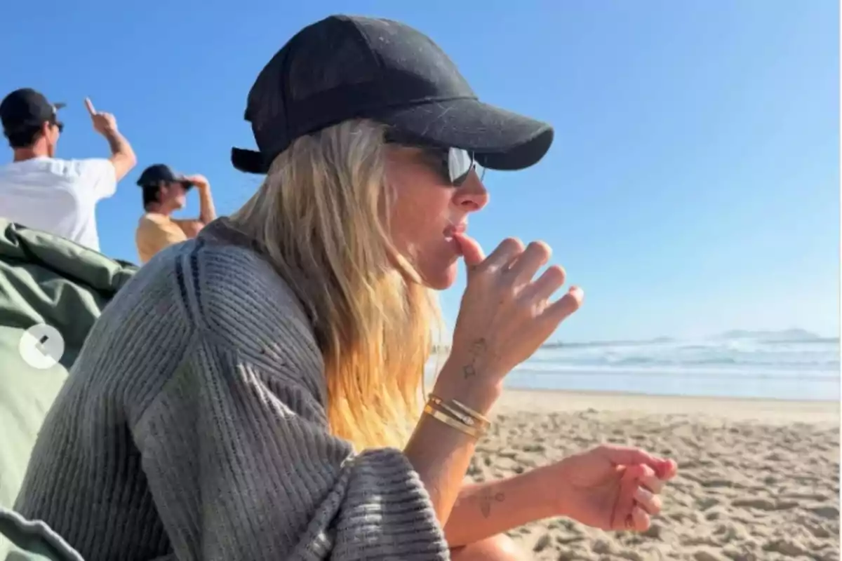 Elsa Pataky, con gorra negra y gafas de sol, sentada en la playa mirando hacia el mar mientras se lleva la mano a la boca Elsa Pataky, con gorra negra y gafas de sol, sentada en la playa mirando hacia el mar mientras se lleva la mano a la boca