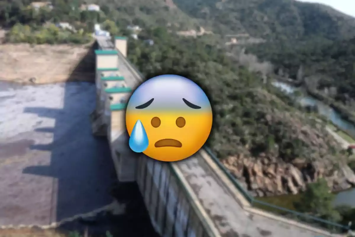 Presa con muy poca agua y un emoji triste con una lágrima en el centro de la imagen