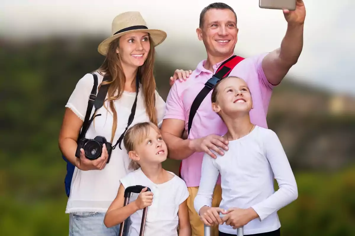Família somrient fent-se una selfie a l’aire lliure durant un viatge, amb maletes i càmera a la mà.