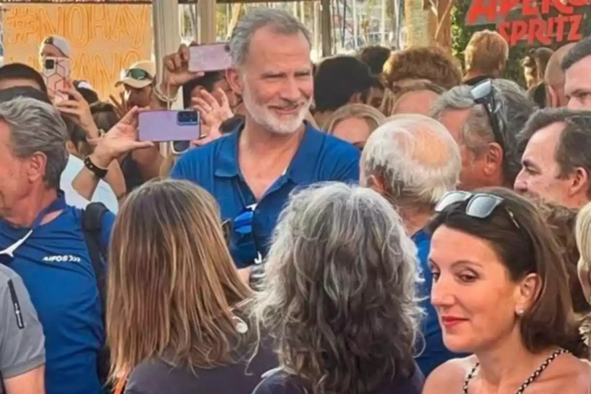 Un home de barba canosa i camisa blava somriu envoltat d’una multitud de persones, algunes de les quals fan fotos amb els seus telèfons mòbils. Un home de barba canosa i camisa blava somriu envoltat d’una multitud de persones, algunes de les quals fan fotos amb els seus telèfons mòbils.