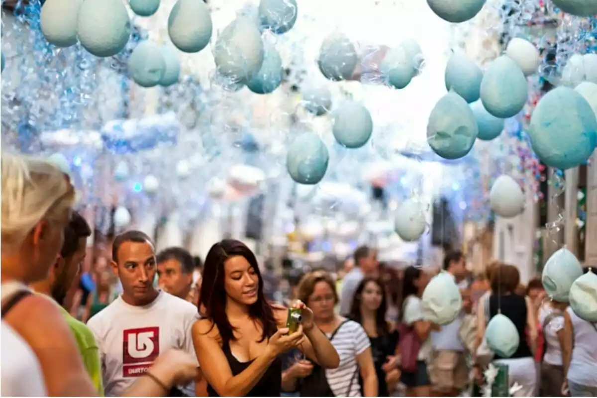 Persones caminant per un carrer decorat amb esferes blaves penjants i ambient festiu