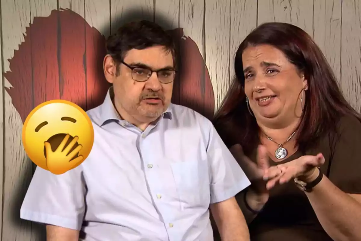 Un home amb expressió seriosa i una dona gesticulant somrient estan asseguts junts davant d’un fons de fusta amb un cor vermell, mentre un emoji de badall apareix sobre l’home.