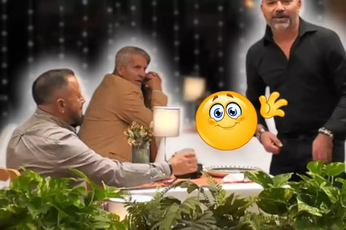 Tres homes interactuen en un restaurant decorat amb plantes i una làmpada de taula, mentre un emoji somrient i fent un gest d'ok apareix en primer pla.