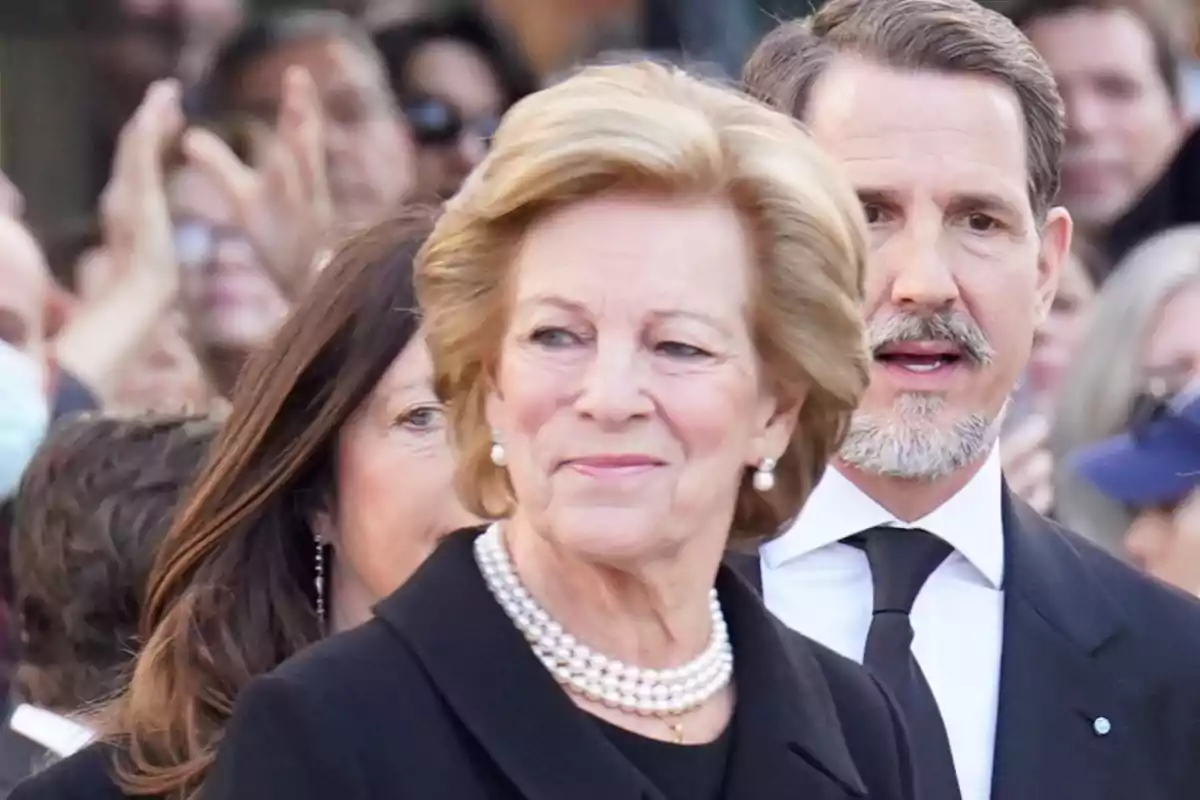 Anne-Marie of Denmark with a pearl necklace and black dress at a formal event surrounded by people Anne-Marie of Denmark with a pearl necklace and black dress at a formal event surrounded by people