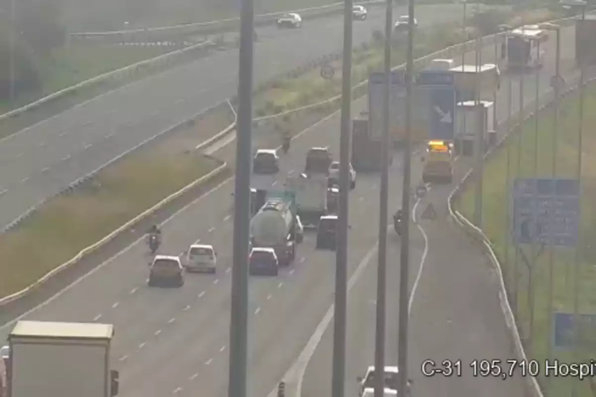 Tráfico denso en una autopista con varios vehículos y un camión de asistencia detenido en el arcén