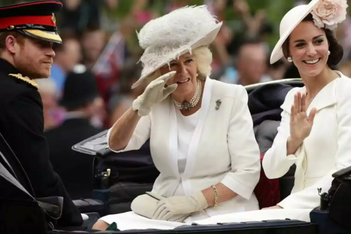 Tres persones elegantment vestides viatgen en un carruatge durant un esdeveniment públic; dues d'elles saluden somrients mentre la multitud observa al fons. Tres persones elegantment vestides viatgen en un carruatge durant un esdeveniment públic; dues d'elles saluden somrients mentre la multitud observa al fons.
