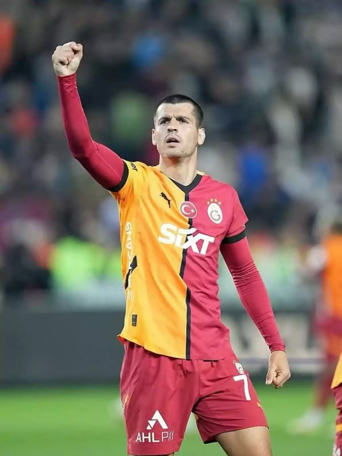 Álvaro Morata con uniforme amarillo y rojo celebrando con el puño en alto en un estadio