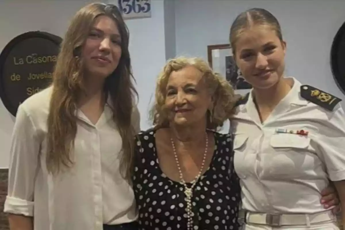 Tres dones posen juntes i somriuen, una d'elles porta uniforme blanc de marina, una altra porta una brusa blanca i la dona del centre porta un vestit negre amb topos blancs i un collaret de perles. Tres dones posen juntes i somriuen, una d'elles porta uniforme blanc de marina, una altra porta una brusa blanca i la dona del centre porta un vestit negre amb topos blancs i un collaret de perles.