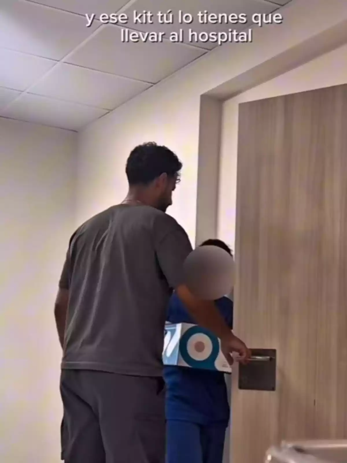 Asraf Beno y una enfermera están entrando a una habitación de hospital, el niño lleva una caja blanca con círculos azules y el rostro difuminado, en la parte superior de la imagen hay un texto en español. Asraf Beno y una enfermera están entrando a una habitación de hospital, el niño lleva una caja blanca con círculos azules y el rostro difuminado, en la parte superior de la imagen hay un texto en español.