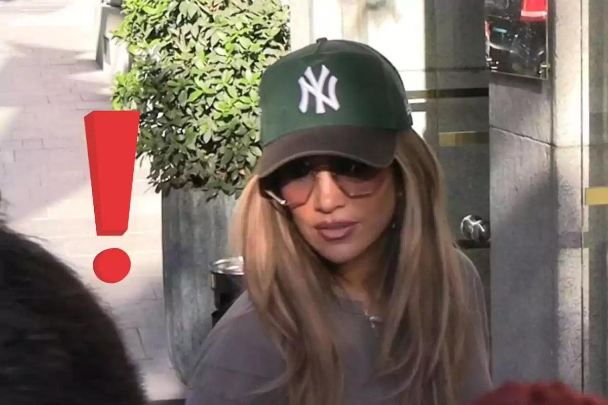 Woman wearing a green Yankees cap and sunglasses walking down the street next to a large red exclamation mark
