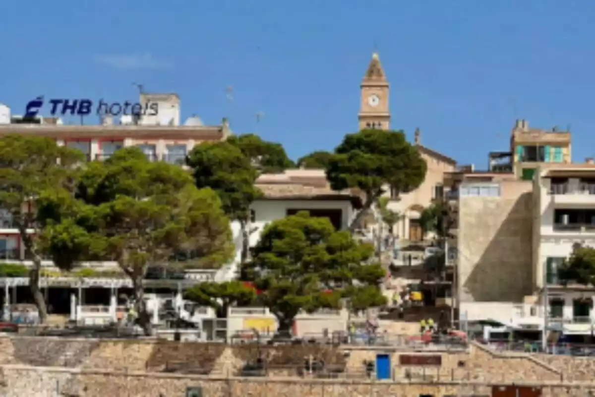 Vista d’un poble costaner amb edificis, arbres i una torre amb rellotge sota un cel serè. Es tracta de Porto Cristo, a Mallorca. Vista d’un poble costaner amb edificis, arbres i una torre amb rellotge sota un cel serè. Es tracta de Porto Cristo, a Mallorca.