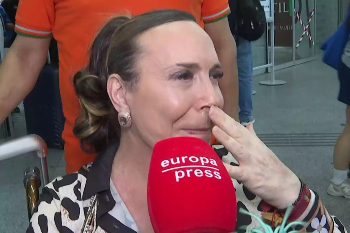 Benita emocionada con lágrimas en los ojos siendo entrevistada por un micrófono rojo de europa press en un lugar público