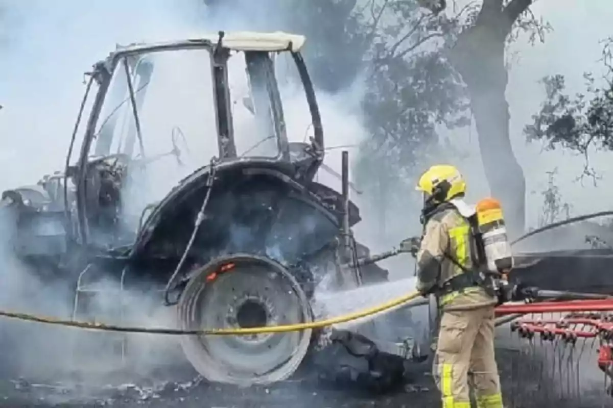 Bombero apaga un incendio en un tractor envuelto en humo en un área al aire libre