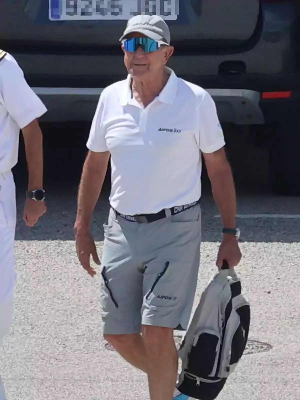 Jaime Rodríguez Toubes amb ulleres de sol esportives, gorra grisa, polo blanc i pantalons curts grisos, caminant a l’aire lliure i portant una motxilla a la mà Jaime Rodríguez Toubes amb ulleres de sol esportives, gorra grisa, polo blanc i pantalons curts grisos, caminant a l’aire lliure i portant una motxilla a la mà