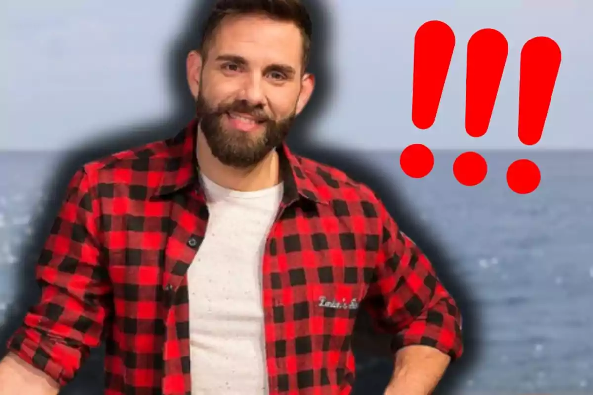 Hombre con barba y camisa de cuadros rojos y negros sonríe frente al mar con tres signos de exclamación rojos grandes a su lado